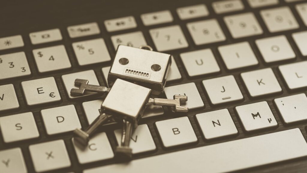 Imagem do bonequinho ícone do chatbots deitado sobre um teclado de computador simulando estar exausto.